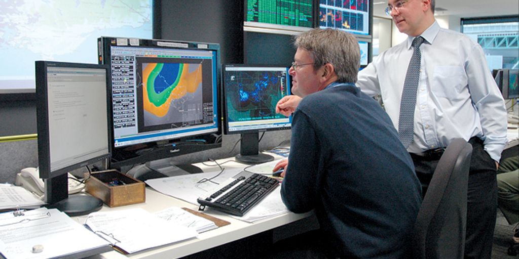 software testing team analyzing data on computer screens in modern office